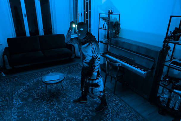 Kirkas valo kädessä, tämä siluetti hahmo etsii läpi salaperäinen pimeässä tilassa valettu sininen sävyjä - Valokuva, kuva