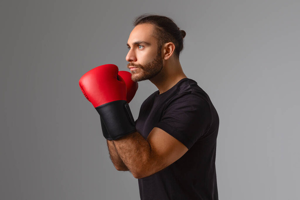 Poważny mężczyzna demonstruje gotowość do sesji bokserskiej z wyrazem twarzy i rękawicami - Zdjęcie, obraz