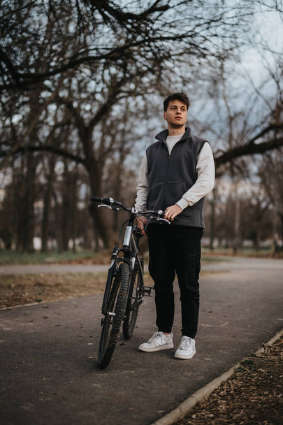 Egy biciklis tinédzser áll egy ösvényen a parkban, szabadidejében a szabadság és a szabadidő érzését árasztva.. - Fotó, kép