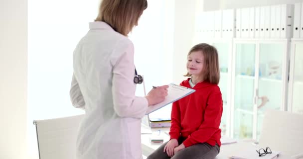 Una niña le sonríe a un pediatra, un primer plano. Examen de la salud de los niños, cámara lenta - Imágenes, Vídeo