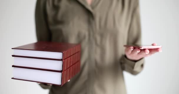 Žena drží červené knihy a telefon, zblízka. Volba mezi tiskovou knihou a e-knihou - Záběry, video