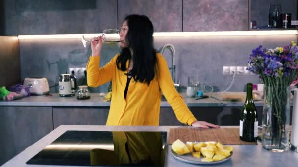 Asijské žena držení sklenice s vínem při pohledu z okna v kuchyni doma. - Záběry, video
