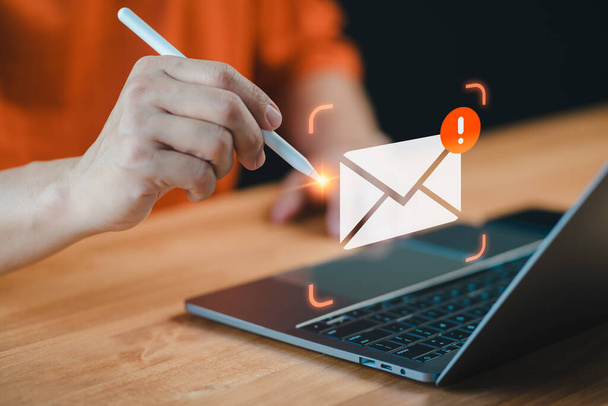 Man multitasks with a pen and laptop, A cautionary email alert notification symbolizes the importance of security measures against errors, ensuring internet protection amidst concerns like junk mail. - Photo, Image