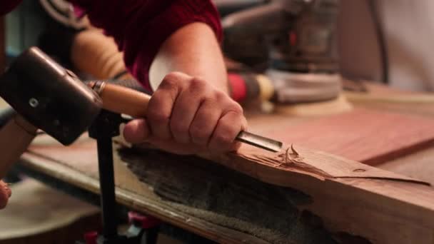 Τεχνίτης σκάλισμα σε ξύλο χρησιμοποιώντας σμίλη και σφυρί σε ξυλουργείο με ακρίβεια. Κατασκευαστής σε studio διαμορφώνοντας ξύλινα κομμάτια με εργαλεία, καθιστώντας την τέχνη του ξύλου, κάμερα - Πλάνα, βίντεο