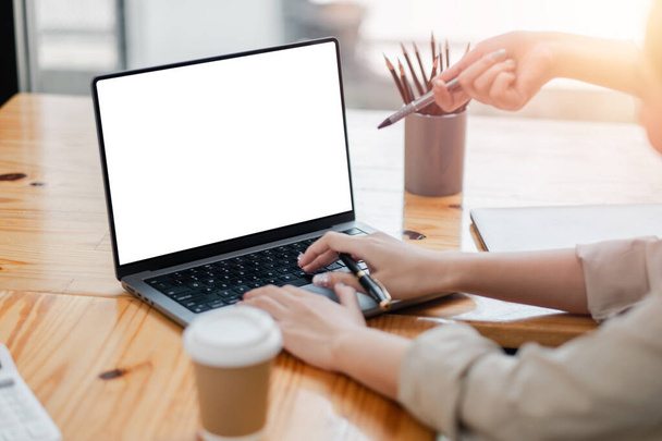 Primer plano de un profesional de las manos escribiendo en un ordenador portátil con una pantalla en blanco, perfecto para maquetas, con una taza de café en el escritorio. - Foto, imagen