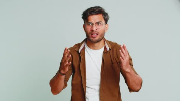 What. Why. Angry Indian man raising hands in indignant expression, asking reason of failure, demonstrating disbelief irritation by troubles. Arabian young guy isolated on gray studio background - Footage, Video