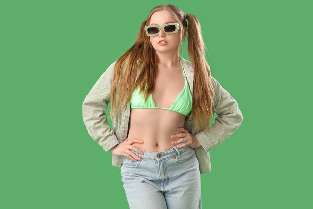 Красива молода жінка в стильному вбранні на зеленому тлі - Фото, зображення