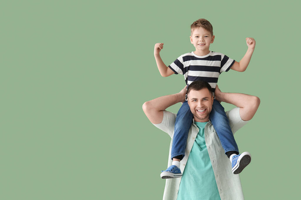 Glücklicher Vater und sein kleiner Sohn zeigen Muskeln auf grünem Hintergrund - Foto, Bild