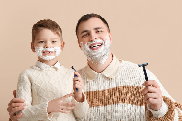 szczęśliwy ojciec i jego mały syn golenie na beżowym tle - Zdjęcie, obraz