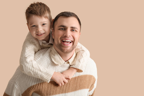 Szczęśliwy ojciec i jego mały syn bawią się razem na beżowym tle - Zdjęcie, obraz