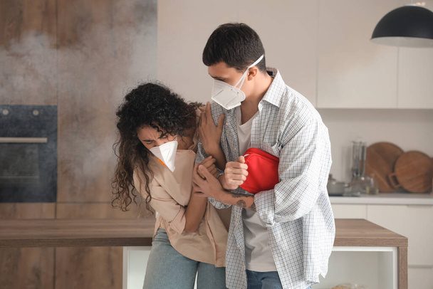 Young couple with first aid kit escaping from burning kitchen - Photo, Image