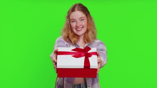 Positive smiling woman presenting birthday gift box stretches out hands, offer wrapped present career bonus, celebrating party, promotion discount sale. Redhead girl isolated on chroma key background - Footage, Video
