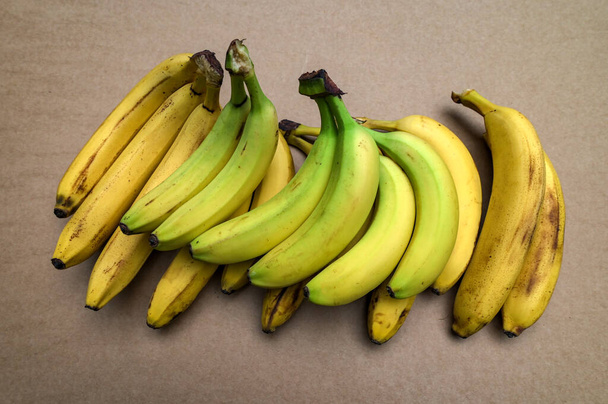 una rama de plátanos frescos sobre la mesa, un primer plano.Un montón de plátano en tonos verdes y amarillos, acostado sobre la mesa, listo para ser vendido. - Foto, Imagen