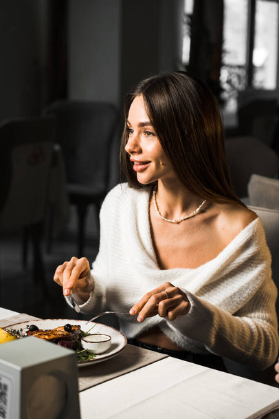 A woman eats a salmon steak in a restaurant.Fish meat cooked on a plate.Food concept - Photo, Image