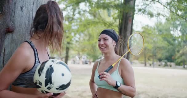 Aktivní sportovní přátelé se těší a konverzaci po příležitostné hře fotbalu a badmintonu v parku. - Záběry, video