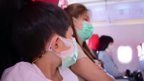 garoto menino e mãe usar máscara estão na cabine de avião - Filmagem, Vídeo