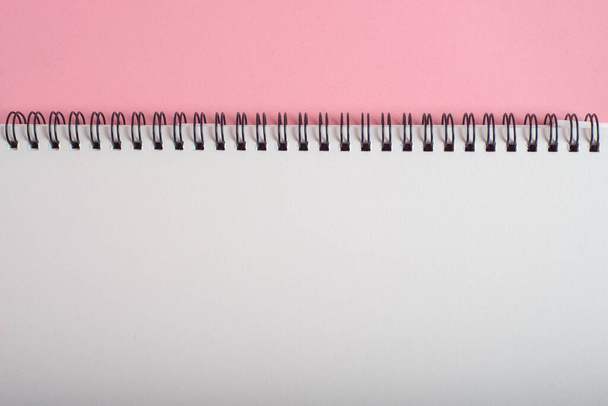 Dubbele spiraal notebook op roze papieren achtergrond. Ruimte voor tekst. - Foto, afbeelding