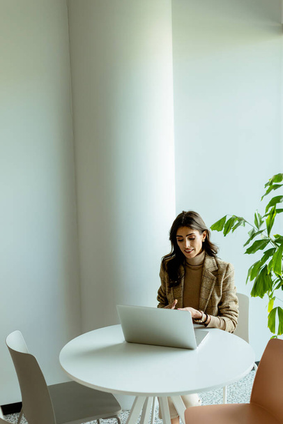 Profesionální žena zaměřená na svou práci v laptopu v elegantní, sluncem zalité kavárně - Fotografie, Obrázek