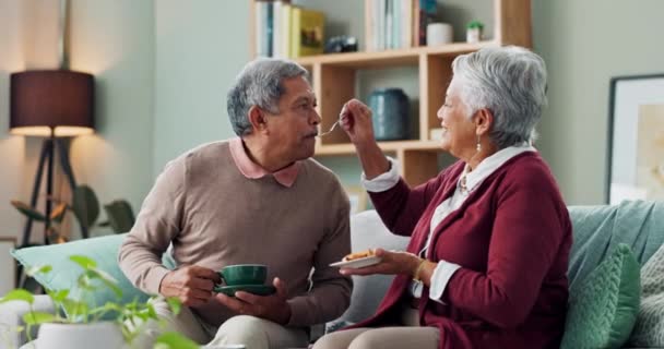 Home, cake and elderly couple with coffee for love, bonding and funny conversation on sofa. Senior people, happy and relax with dessert for afternoon communication, discussion and peace in retirement. - Footage, Video