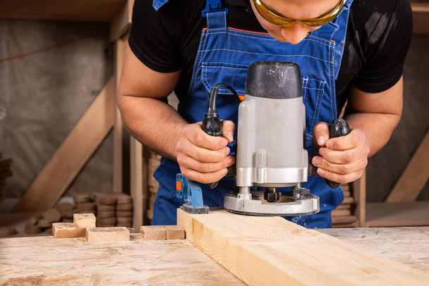 Mies puuseppä käyttäen sähköhiomakone kiillottaa puulankku puusepän työpaja - Valokuva, kuva