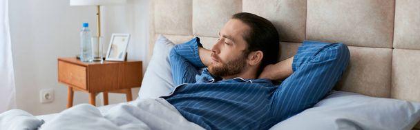 Ένας άντρας ξαπλωμένος ήσυχα στο κρεβάτι με το κεφάλι στο μαξιλάρι. - Φωτογραφία, εικόνα