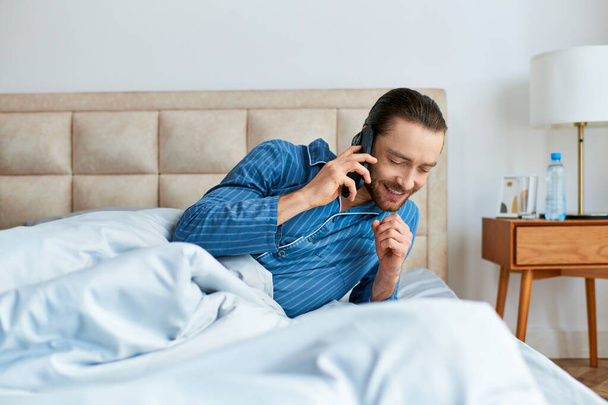 Hombre guapo en la cama habla por teléfono celular. - Foto, imagen