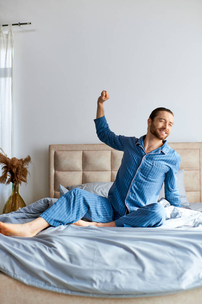 Muž v pyžamu sedí na posteli v poklidném ranním okamžiku. - Fotografie, Obrázek