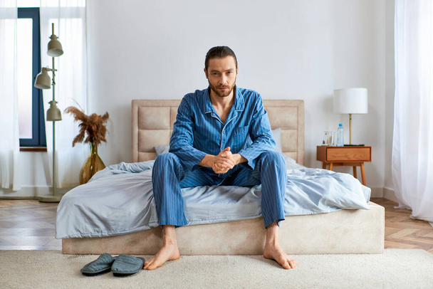 Όμορφος άντρας με πιτζάμες πάνω σε ένα κρεβάτι.. - Φωτογραφία, εικόνα