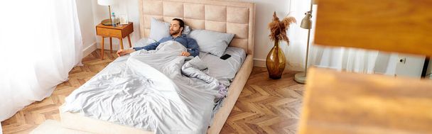 Egy férfi békésen fekszik az ágyán egy kényelmes hálószobában.. - Fotó, kép
