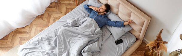Ein Mann liegt friedlich auf einem Bett mit einer kuscheligen Decke. - Foto, Bild