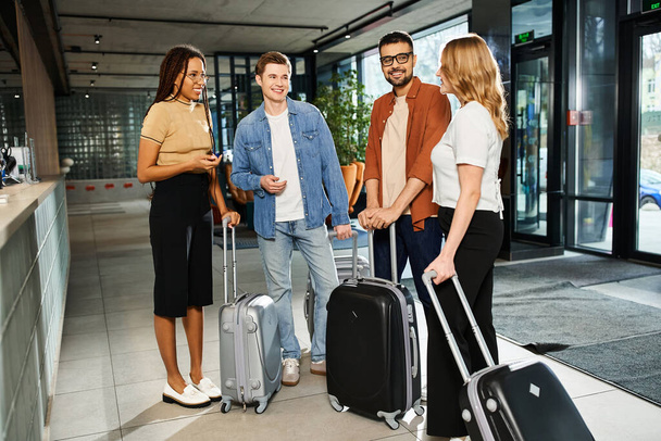 Multikulturelle Kollegen in Freizeitkleidung stehen während einer Geschäftsreise mit Gepäck in einer Hotellobby herum. - Foto, Bild
