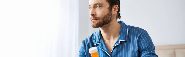 Hombre guapo en camisa azul sosteniendo la botella de pastillas. - Foto, imagen