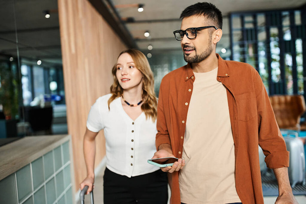 Um homem e uma mulher em roupas casuais, passeando por um corredor do hotel durante uma viagem corporativa. - Foto, Imagem