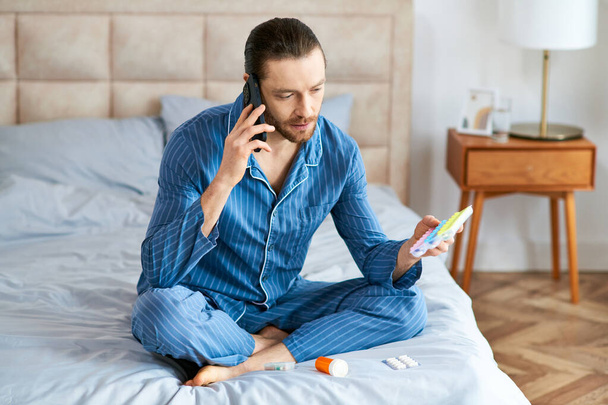Un hombre sentado en una cama, ocupado en una llamada telefónica. - Foto, imagen