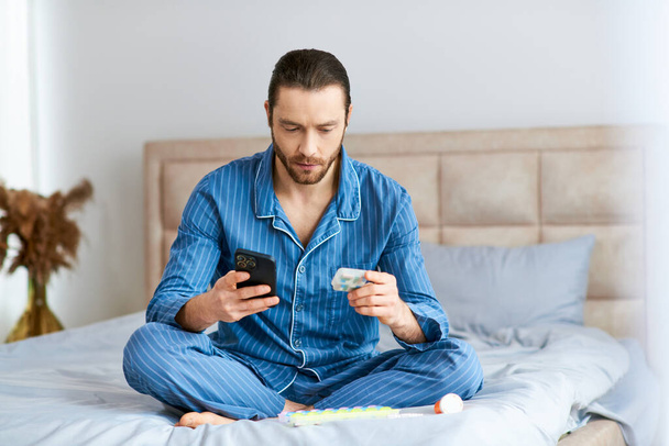 Un hombre absorto en su teléfono celular mientras está sentado en una cama. - Foto, imagen