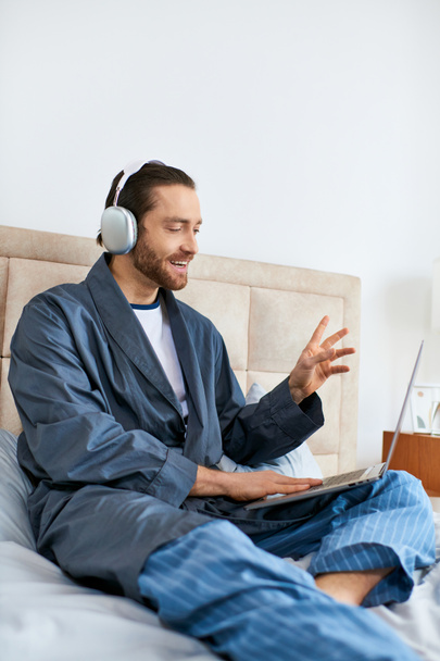 Man with headphones, laptop on bed, morning routine. - Valokuva, kuva