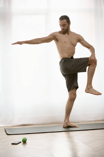 Bonito homem praticando ioga em um tapete em sua casa durante a manhã. - Foto, Imagem
