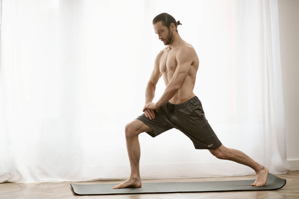 Práctica de yoga en casa; un hombre, guapo y concentrado, se equilibra con gracia en una esterilla. - Foto, imagen