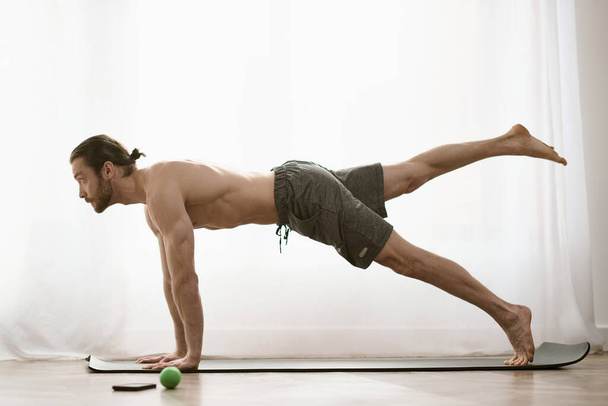 At home, a handsome man focuses on his core by doing a plank. - Photo, Image