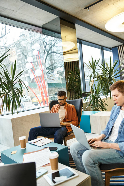 Un gruppo di colleghi pensa e lavora sui laptop in un moderno spazio di lavoro aziendale, incarnando le dinamiche del team di start-up. - Foto, immagini