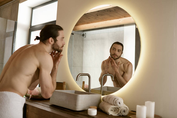 Όμορφος άντρας μπροστά στον καθρέφτη του μπάνιου στο σπίτι.. - Φωτογραφία, εικόνα