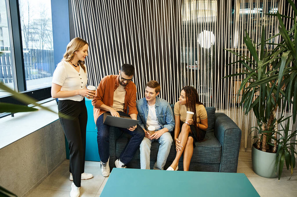 A group of colleagues from a startup team work together around a stylish blue couch in a modern business setting. - Photo, Image