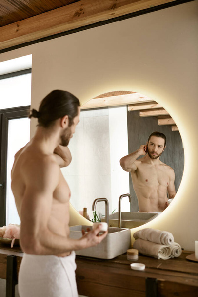 男はトイレの鏡の前に立って,朝のスキンケアのルーチンに従事する. - 写真・画像