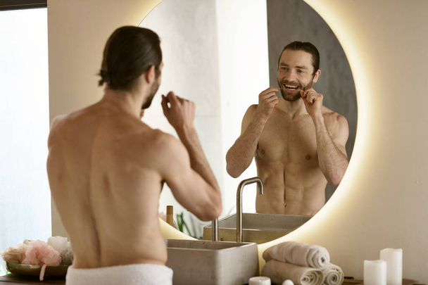 Ein Mann mit Zahnseide vor dem Spiegel während seiner morgendlichen Routine. - Foto, Bild