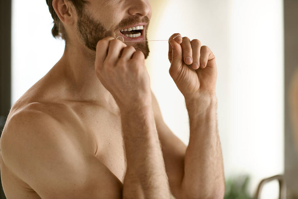 Hombre sin camisa realizando rutina de higiene dental matutina frente a un espejo. - Foto, imagen