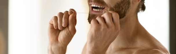 Gömleksiz bir adam dişlerini aynanın önünde fırçalar, sabah rutininin bir parçasıdır.. - Fotoğraf, Görsel
