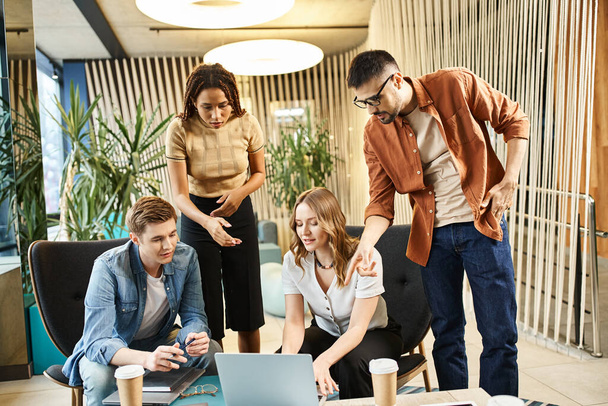 Chers collègues dans un espace de coworking, une équipe de start-up s'engageant dans une stratégie d'entreprise moderne, se blottissant autour d'un ordinateur portable pour la collaboration. - Photo, image