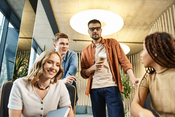 Un grupo diverso de colegas en un moderno espacio de coworking, haciendo una lluvia de ideas y colaborando en torno a una mesa. - Foto, imagen