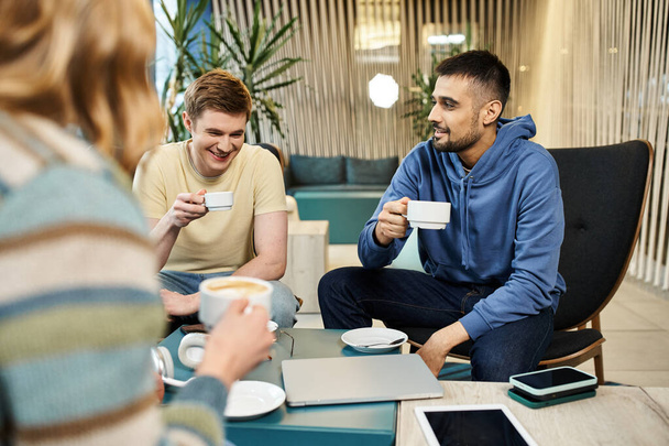 Colegas de un equipo de startups se involucran en un descanso casual para tomar café, discutiendo ideas y vinculándose con tazas de café. - Foto, imagen