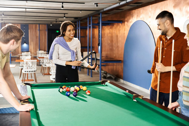 Um grupo de colegas de uma equipe de startup desfrutando de um jogo de bilhar em um ambiente de negócios moderno. - Foto, Imagem